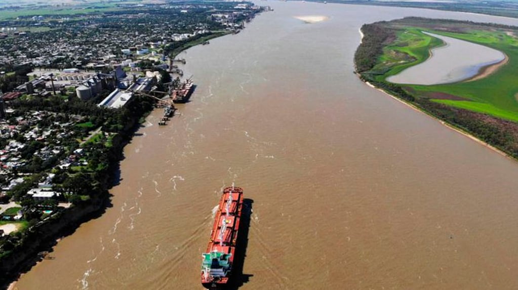 Un buque ultramarino navega frente al complejo agroportuario sobre el río Paraná. La presencia de CRA en el órgano de control busca auditar calados, tarifas y condiciones de navegabilidad